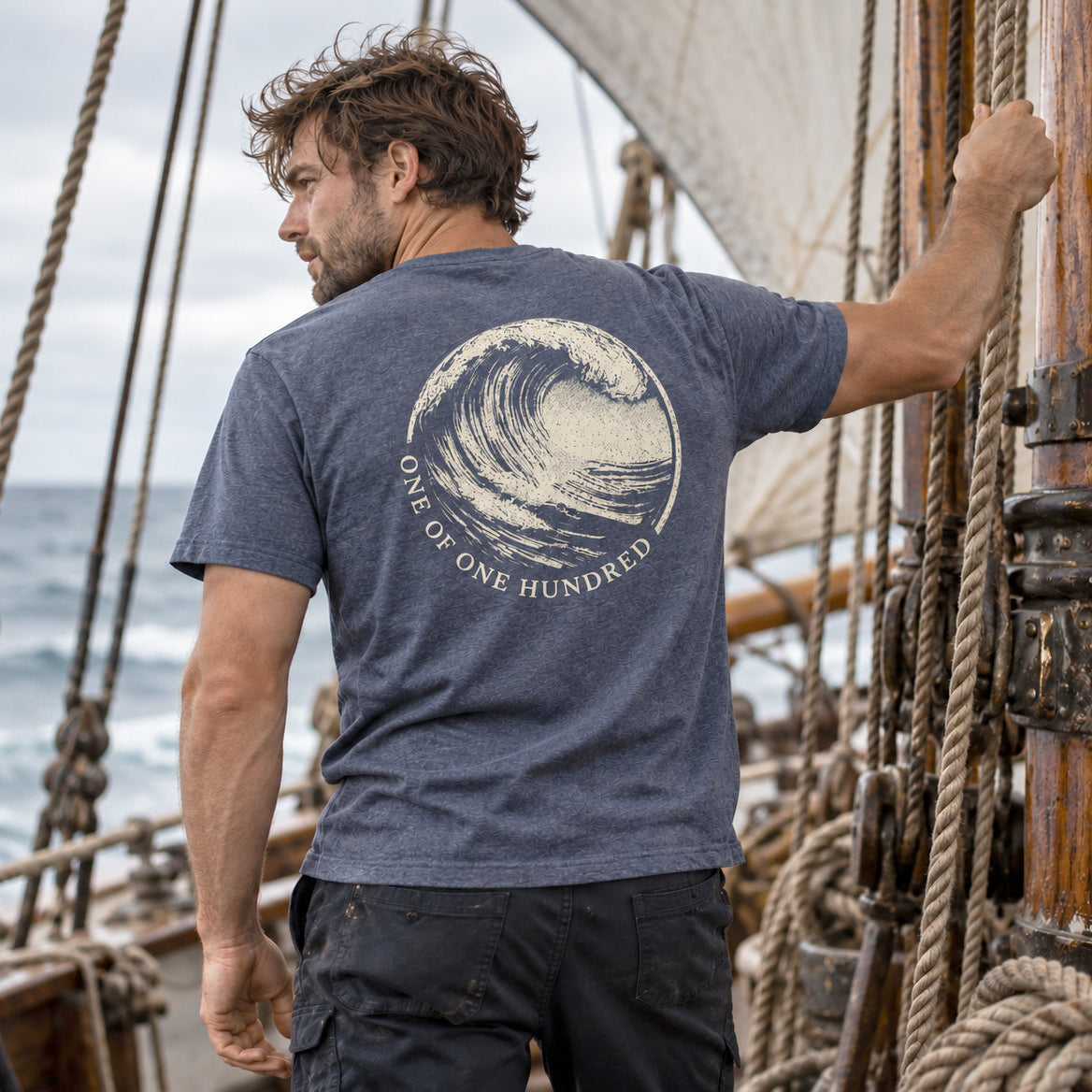 Evelyn Heather Navy T-Shirt by Sauce & Brown, featuring One of One Hundred wave back print, worn on a sailing ship.