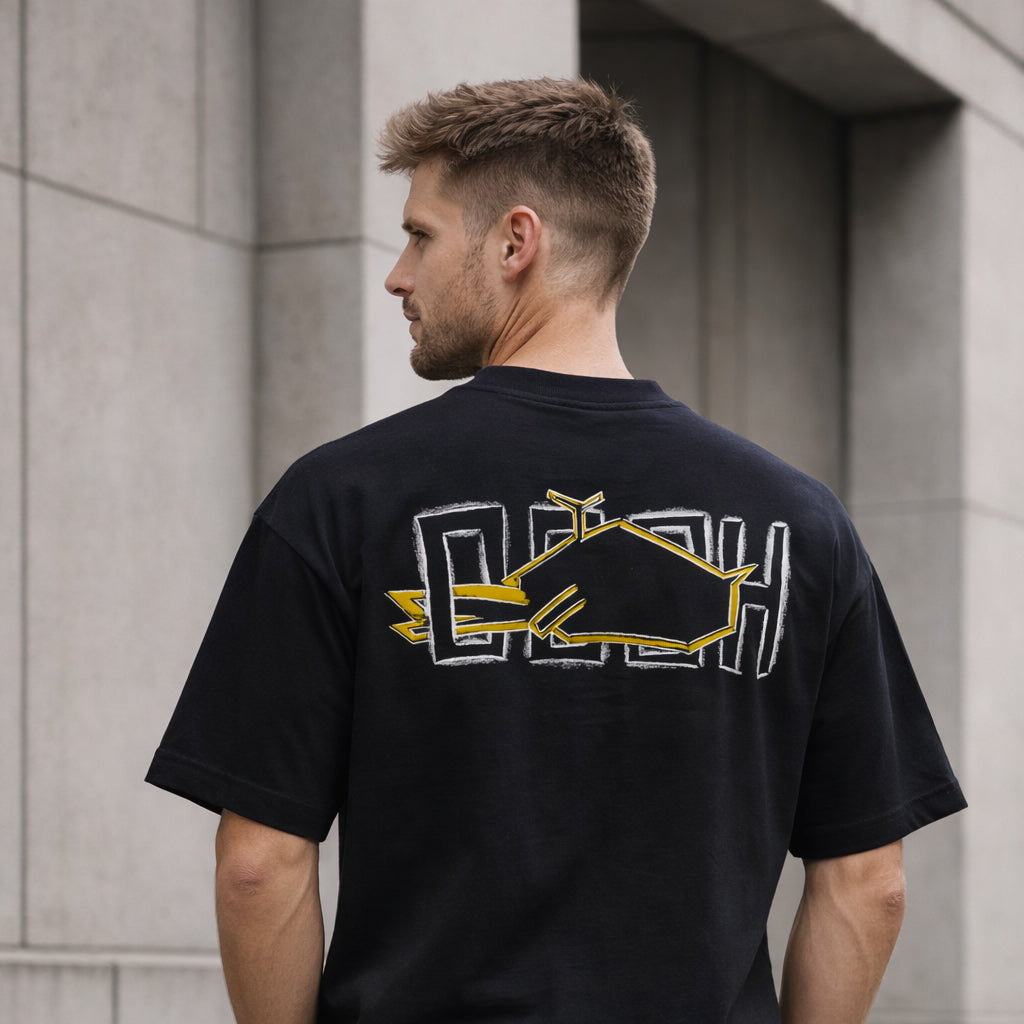 Model wearing Magnitude Box T-Shirt in black with yellow back graphic outdoors by Sauce & Brown