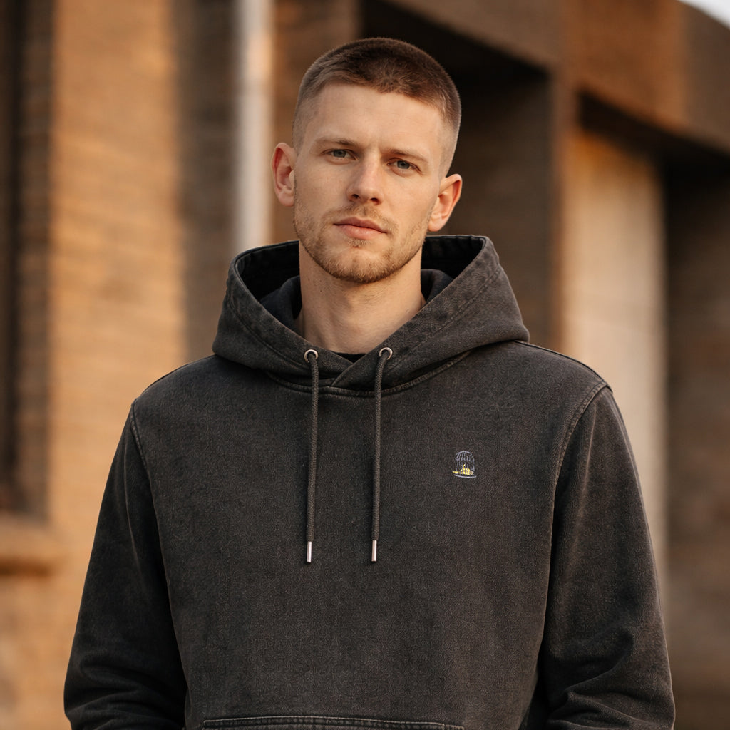 Male model wearing Forge Hoody black vintage washed hoodie outdoors in natural light 300 GSM organic cotton