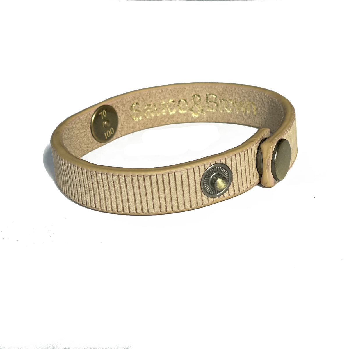 Angled view of beige leather band showing snap fastening and logo by Sauce & Brown