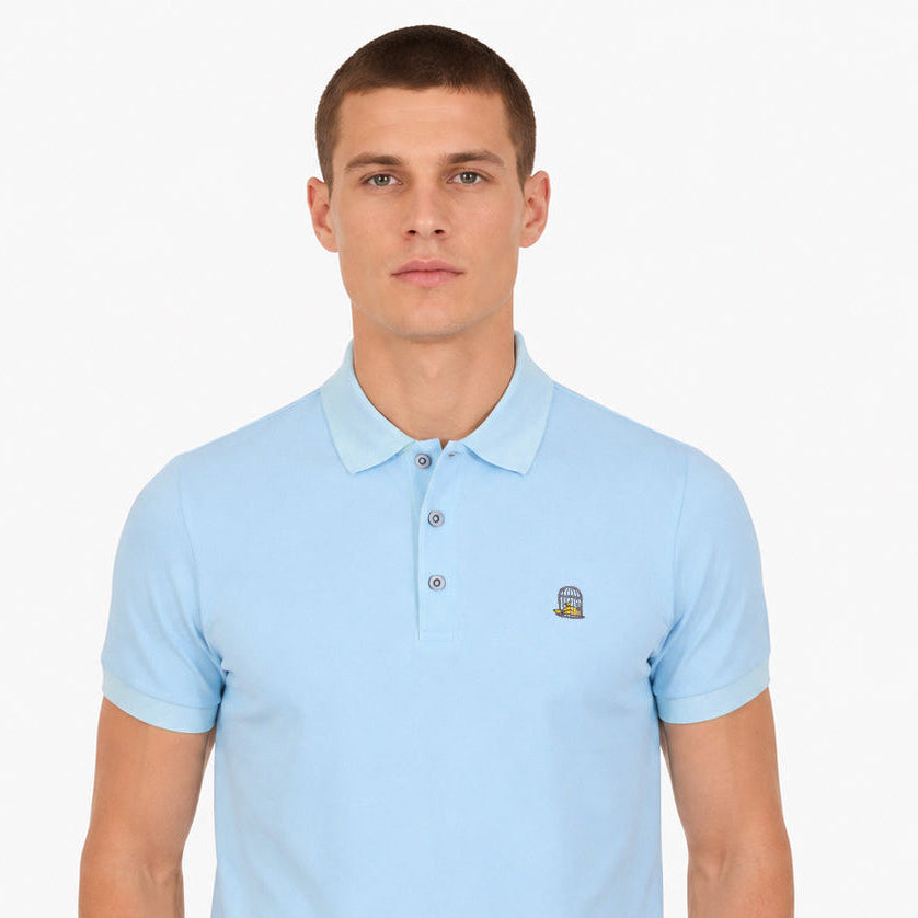 White male model wearing the Sauce & Brown Calma light blue polo shirt in a front-facing studio shot against a clean white background.