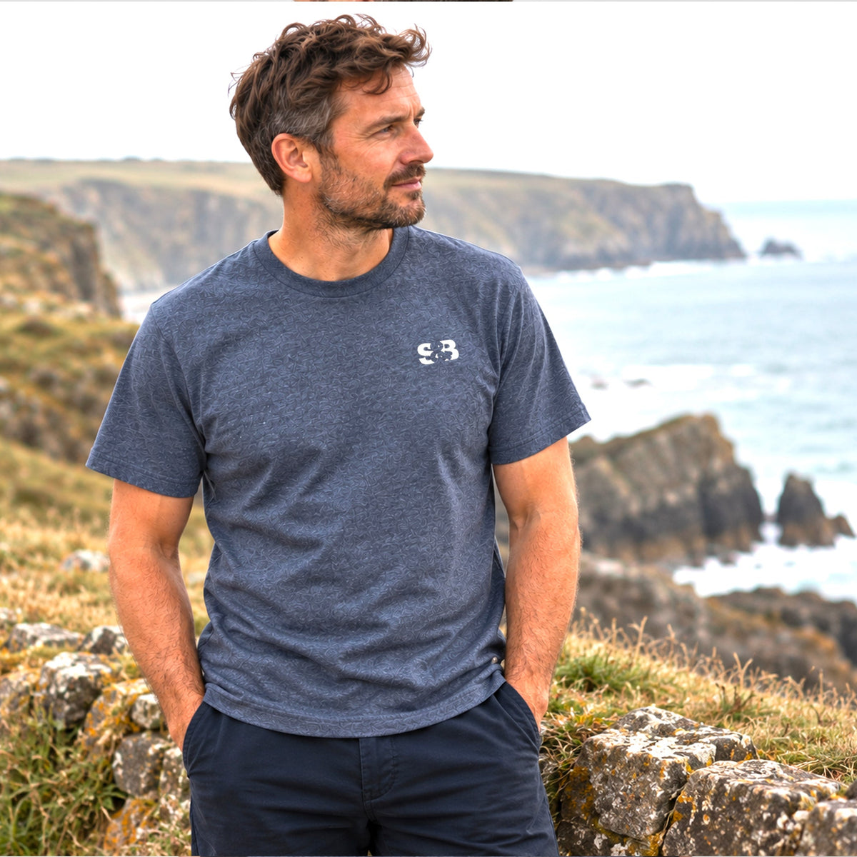 Evelyn Heather Navy T-Shirt by Sauce & Brown, showing the S&B chest print, worn on the British coast.