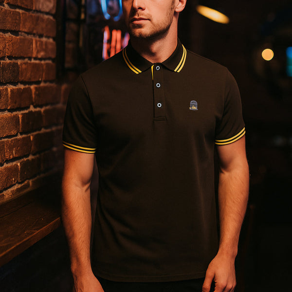 Man wearing a bl polo shirt with yellow tipping against a dark backgroundrown