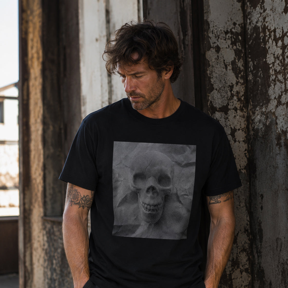 Male model wearing the Sauce & Brown Relic black T-shirt with grayscale skull graphic in a weathered industrial setting.