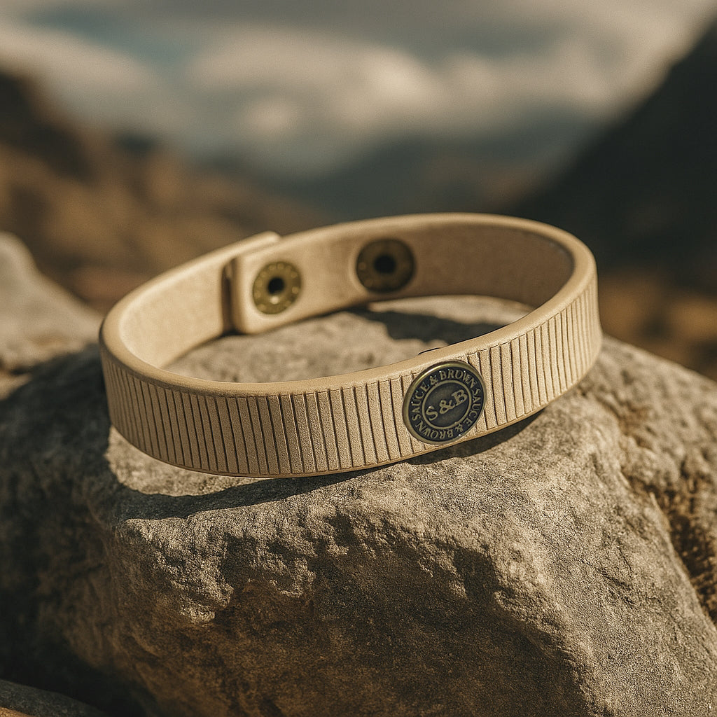 Beige leather band with logo placed on rock outdoors by Sauce & Brown