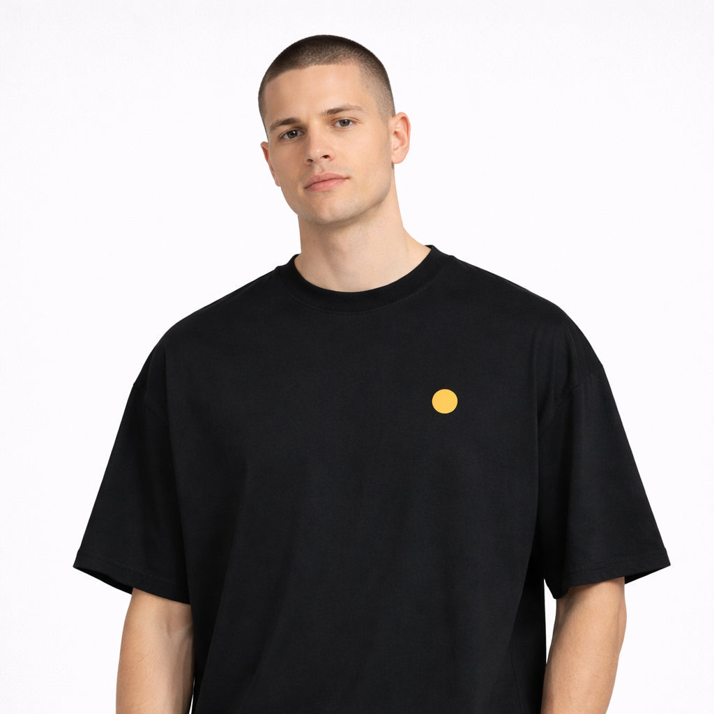Front view of Magnitude Box T-Shirt in black with chest logo worn by model by Sauce & Brown