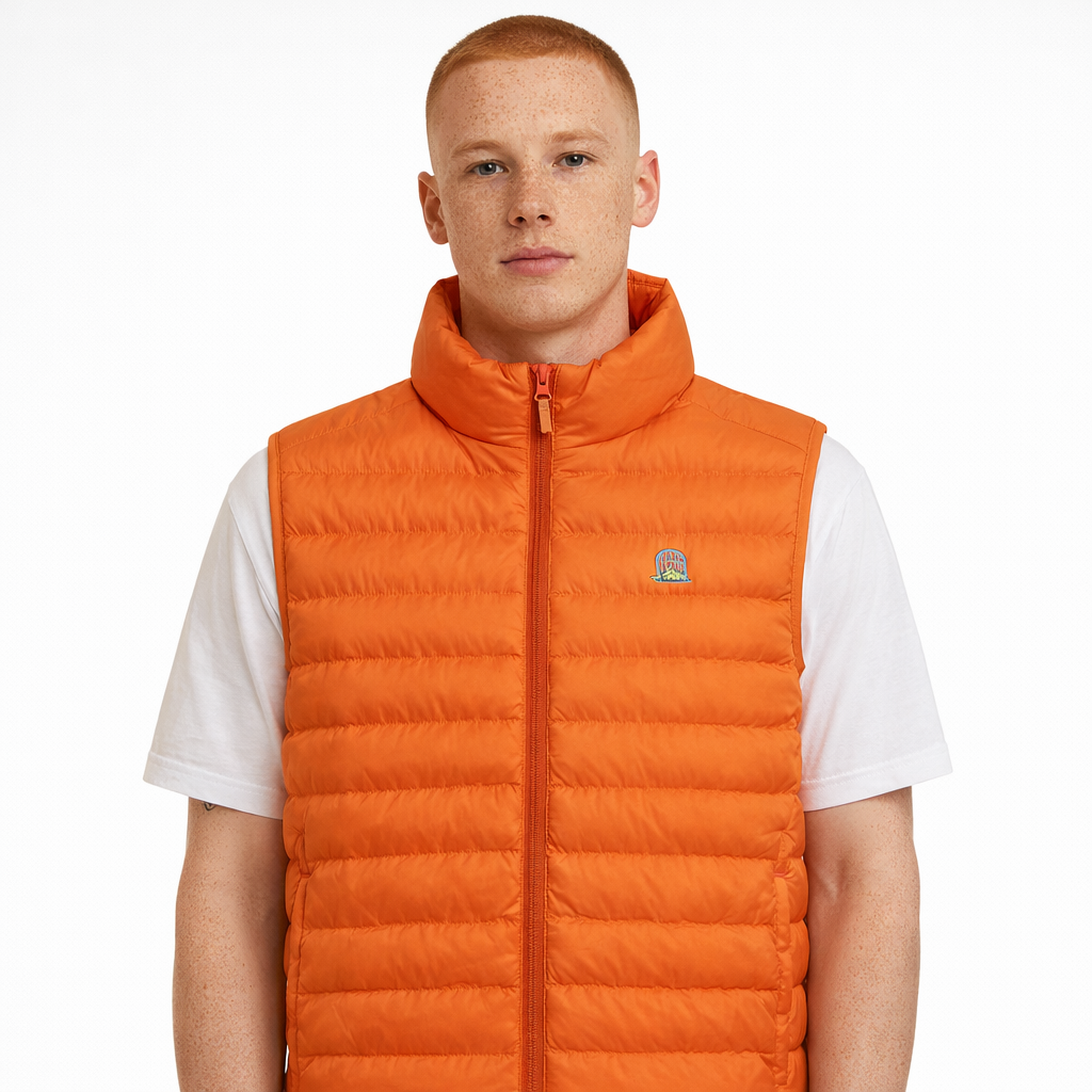 Sol Gilet in orange with embroidered chest logo worn by model by Sauce & Brown