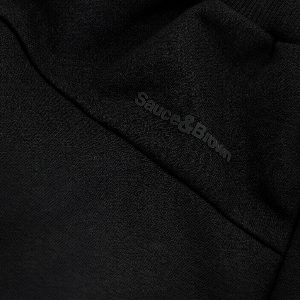 Close-up logo detail on Straight Leg Joggers in black by Sauce & Brown