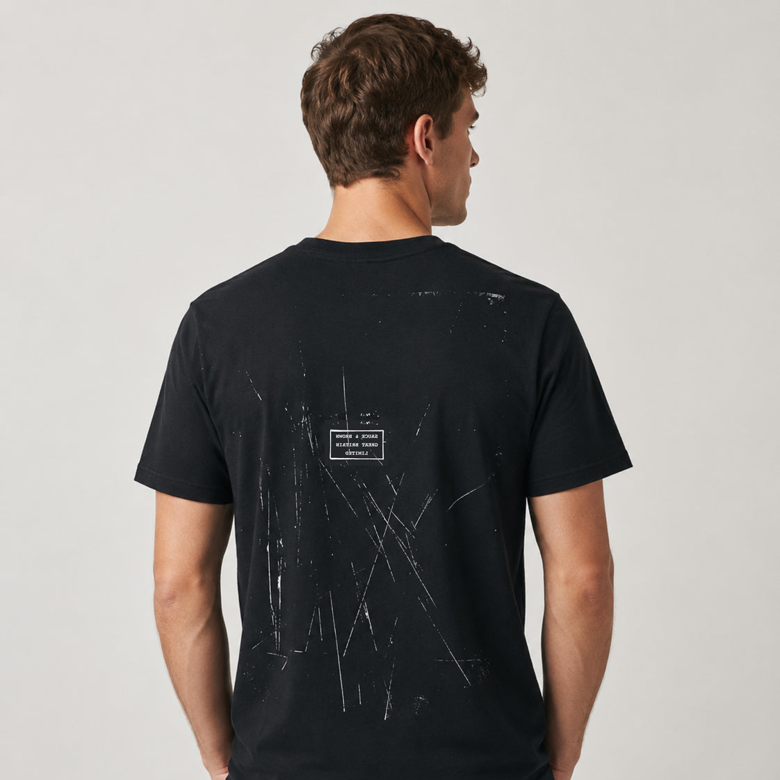 Rear studio photograph of a male model wearing the Sauce & Brown Scratchback black T-Shirt showing the Scratchback back print.