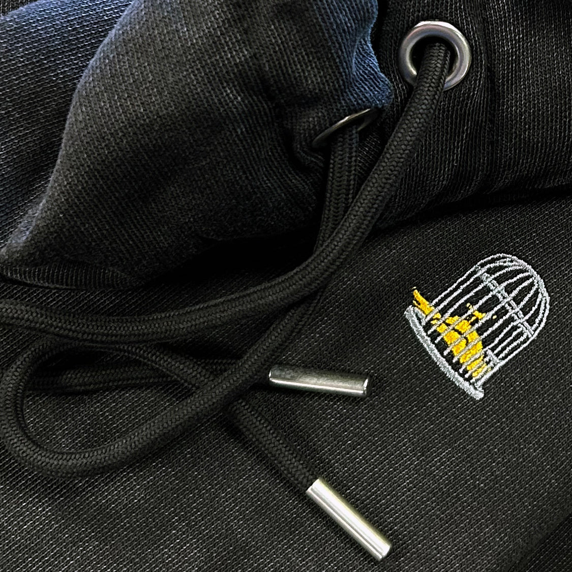 Forge Hoody close up detail black vintage washed hoodie drawcord metal tips embroidery organic cotton