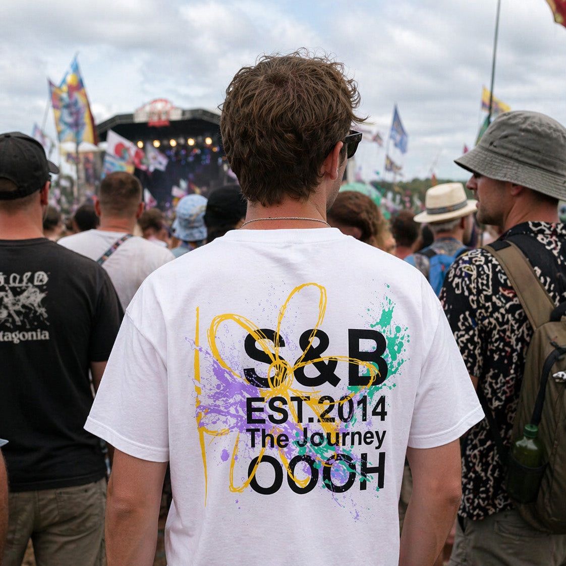 White graphic T-shirt with S&B print worn at Glastonbury Festival, lifestyle crowd shot