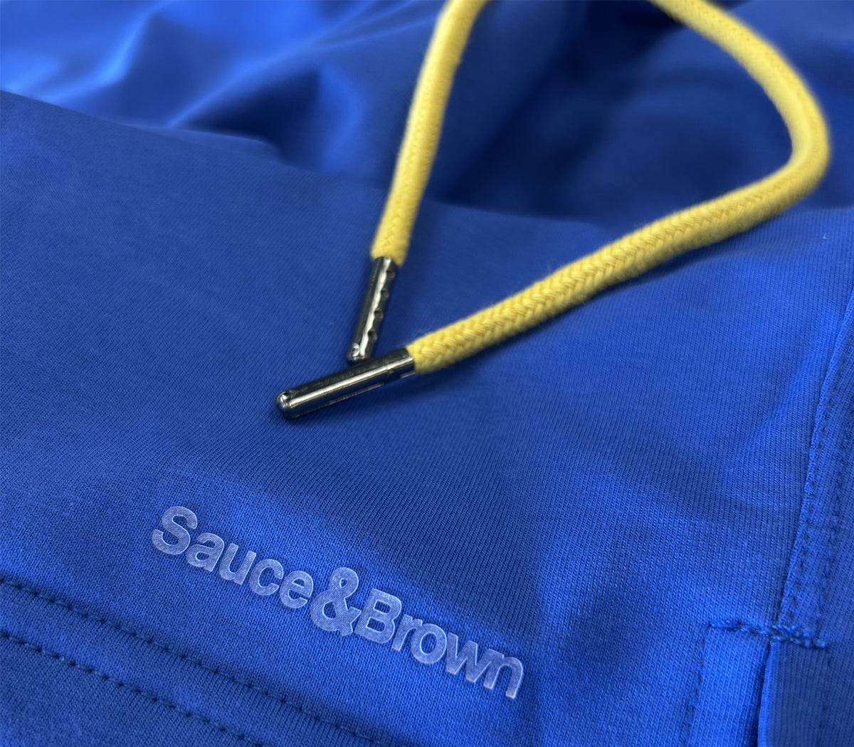 Close-up of blue Piero shorts showing yellow drawstring and Sauce & Brown logo detail